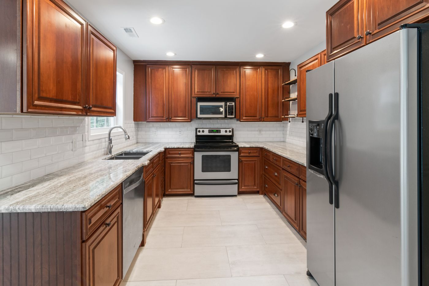 U-shaped kitchen with warm wood cabinetry and stainless appliances